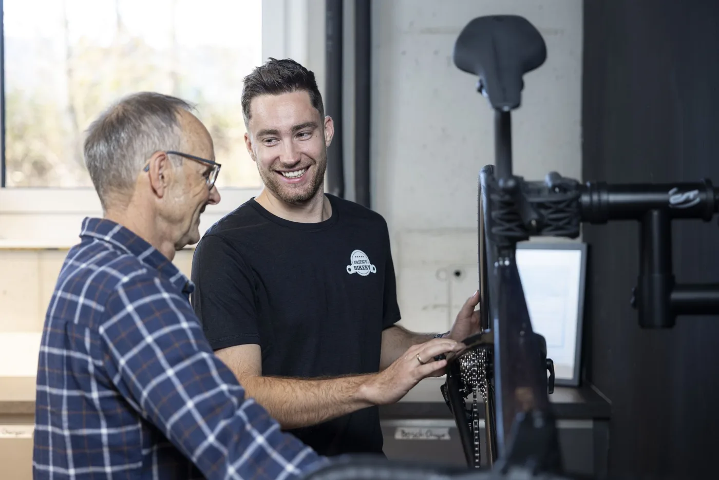 A staff member advising a smiling customer over a bike
